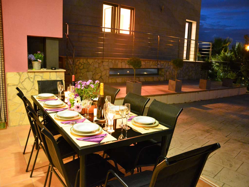 Villa Sitges de noche con comedor exterior.